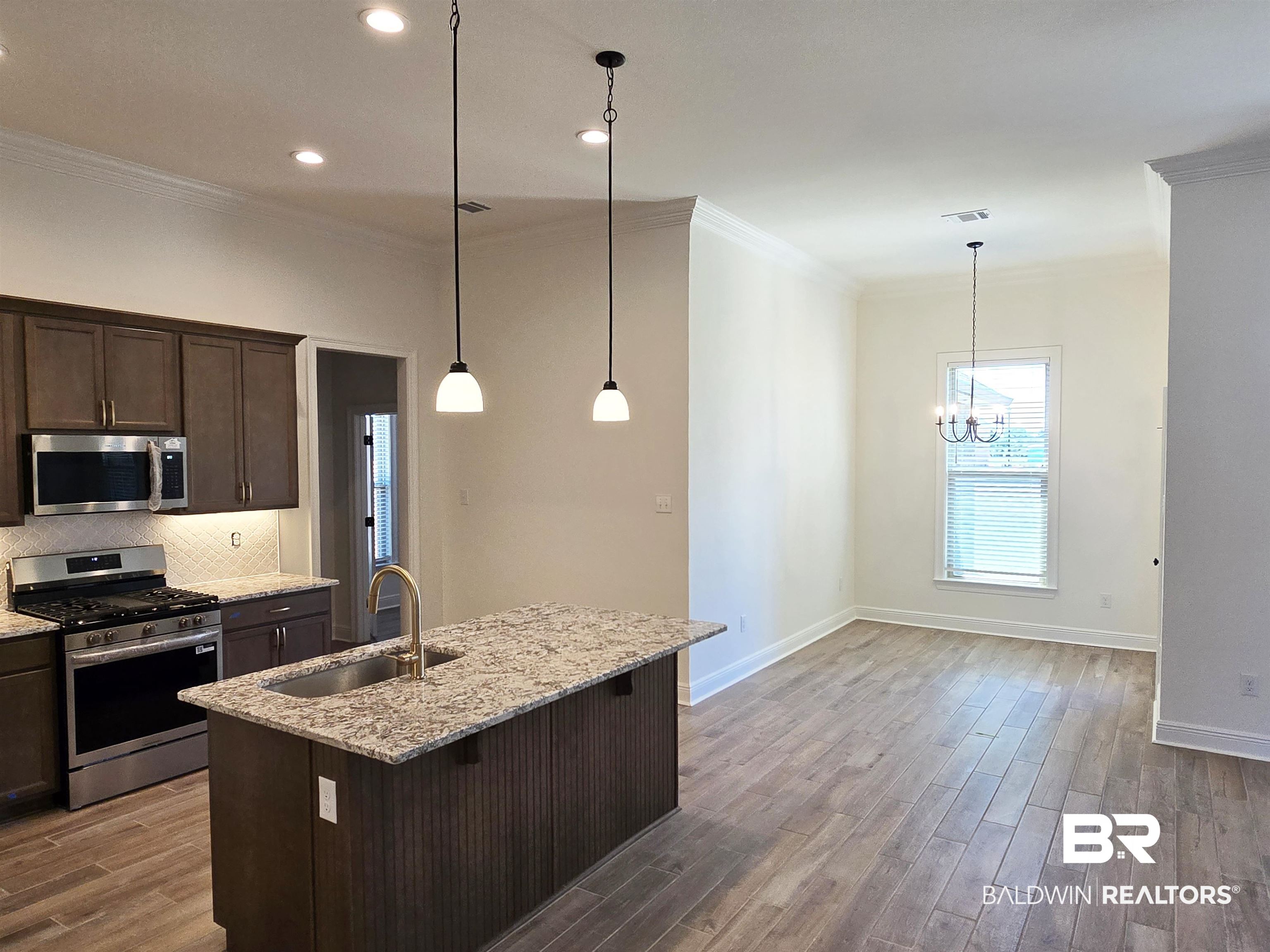 11178 Bonaventure Avenue Daphne, AL 36526 - Photo 3 of 20 Kitchen featuring stainless steel appliances, light stone countertops, dark wood finish cabinetry, crown molding, and dark wood finished floors