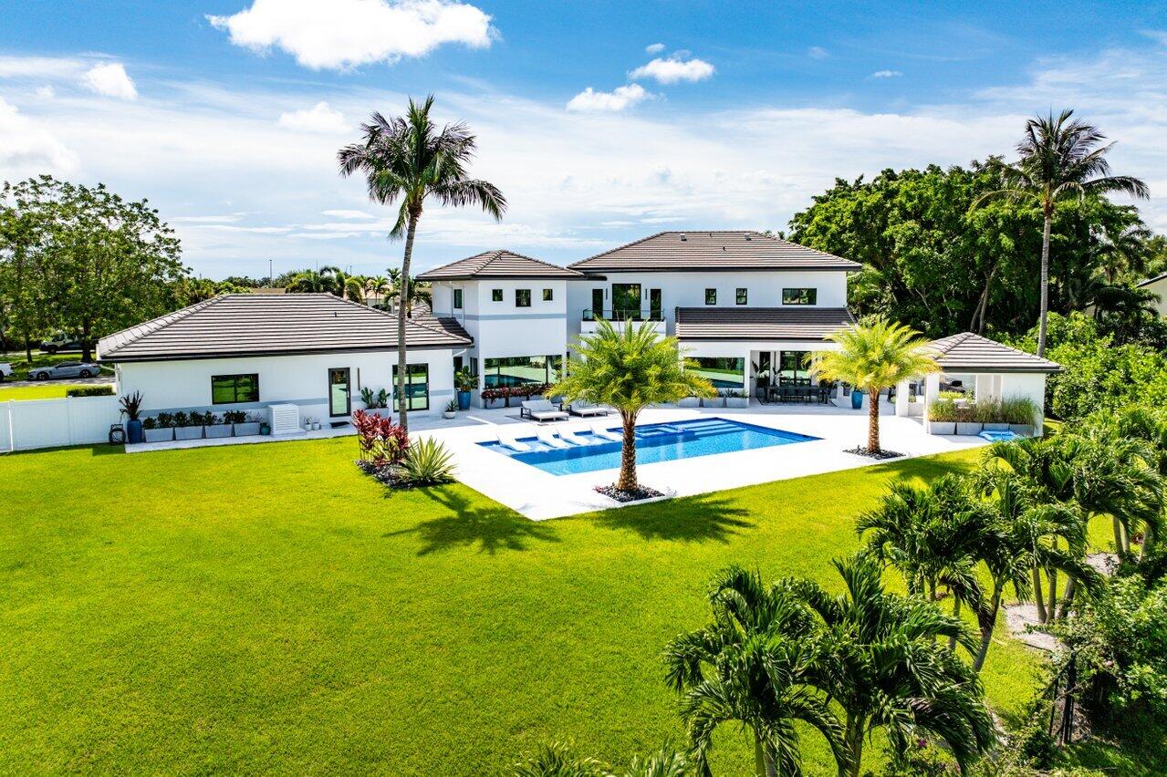 8387 Sawpine Road Delray Beach, FL 33446 - Photo 2 of 57 a view of a swimming pool with lawn chairs under an umbrella