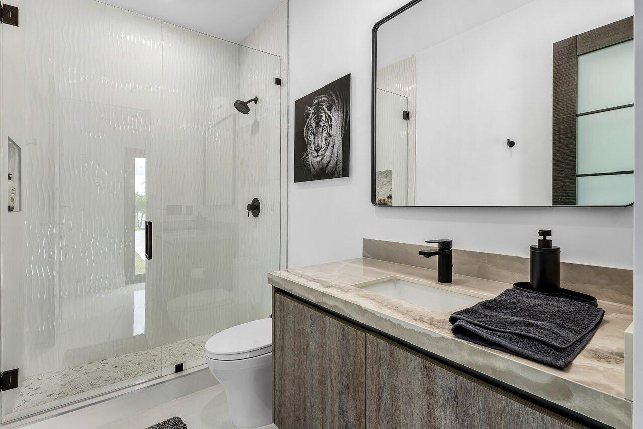 8387 Sawpine Road Delray Beach, FL 33446 - Photo 21 of 57 a bathroom with a granite countertop sink toilet a mirror a vanity and shower