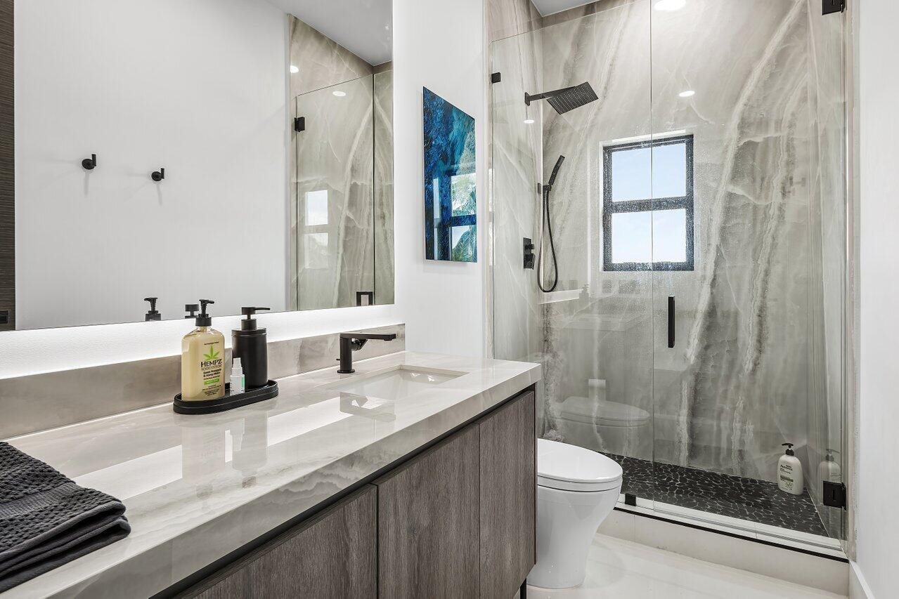 8387 Sawpine Road Delray Beach, FL 33446 - Photo 27 of 57 a bathroom with a double vanity sink toilet and shower