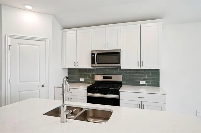 a kitchen with granite countertop white cabinets and stainless steel appliances