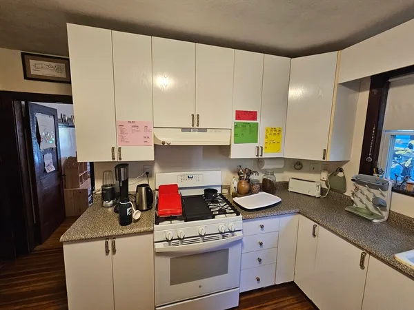 a kitchen with a sink dishwasher stove and white cabinets