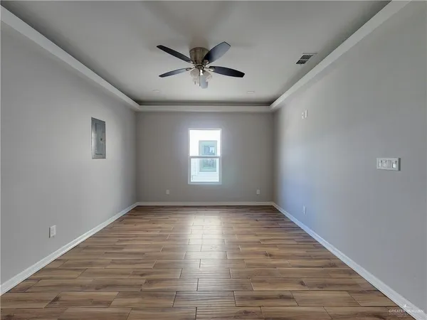 a view of empty room with wooden floor and fan