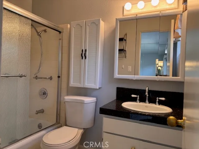 a bathroom with a granite countertop sink toilet a mirror and shower