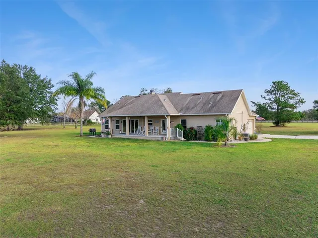 a view of a big house with a big yard and palm trees