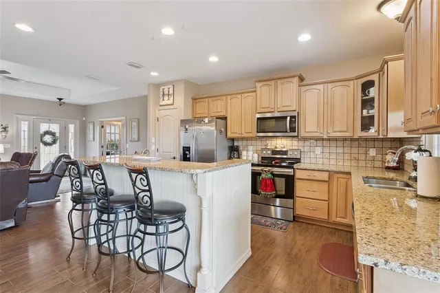 a kitchen with stainless steel appliances granite countertop a stove top oven a sink a dining table and chairs