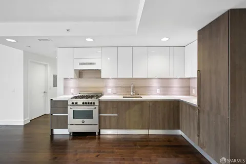 a open kitchen with stainless steel appliances granite countertop a stove top oven a sink dishwasher a dining table and chairs with wooden floor