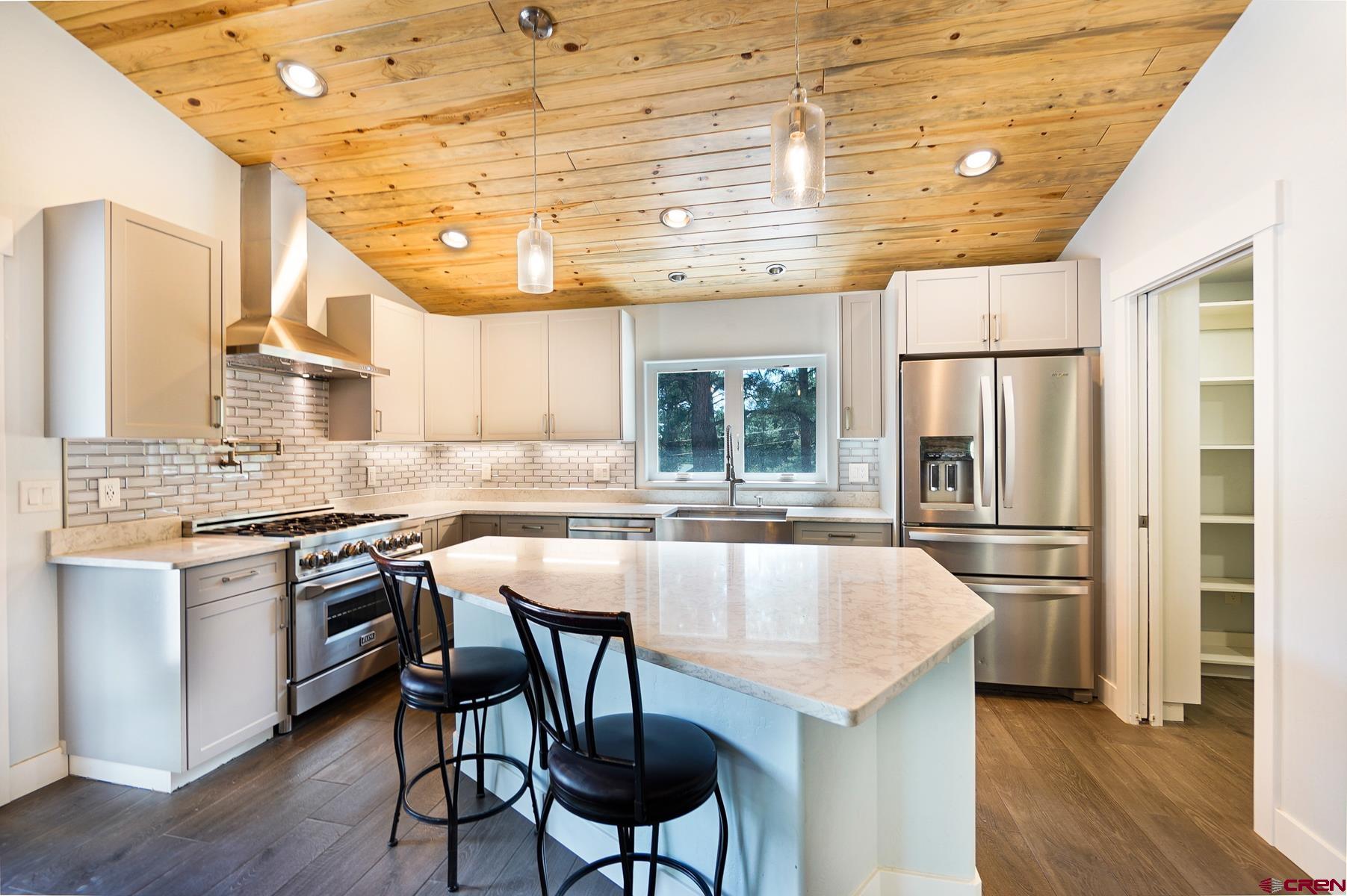 120 Sortais Road Durango, CO 81301 - Photo 3 of 21 a kitchen with stainless steel appliances granite countertop a stove a refrigerator a kitchen island and chairs in it