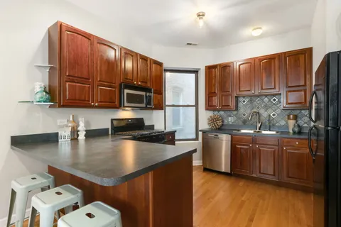 a kitchen with stainless steel appliances granite countertop a sink dishwasher stove and refrigerator with wooden floor
