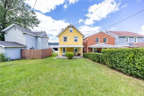 a view of a house with a big yard plants and large trees