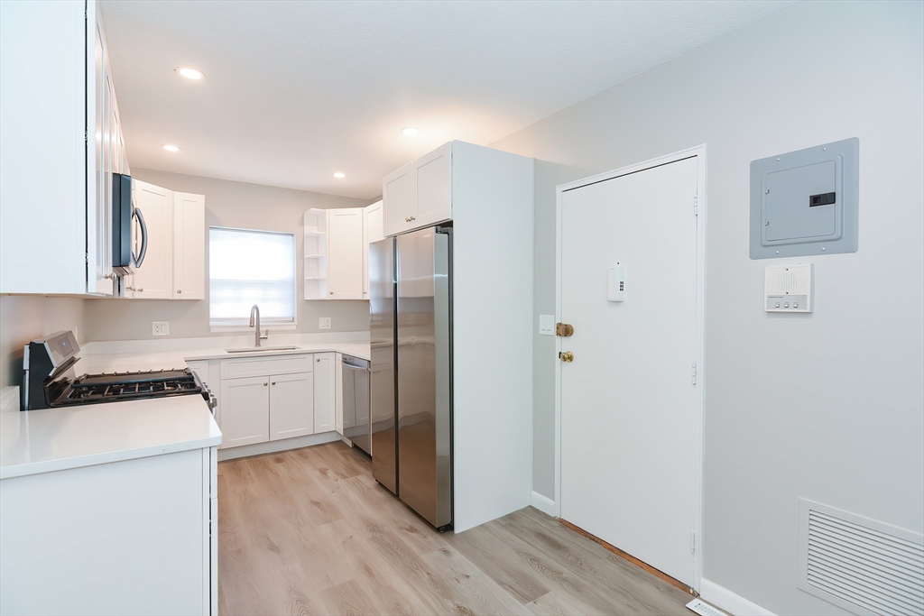 141 Lake Shore Road, Unit 1 Boston, MA 02135 - Photo 4 of 42 a kitchen with a refrigerator a sink and cabinets