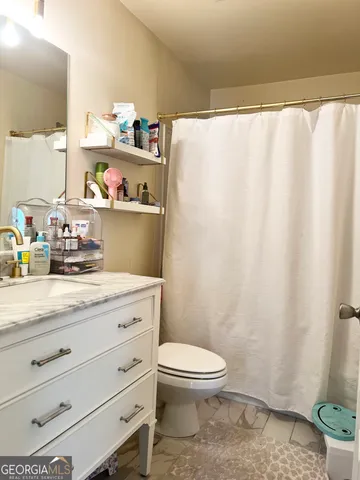 a bathroom with a granite countertop sink a toilet and a shower curtain
