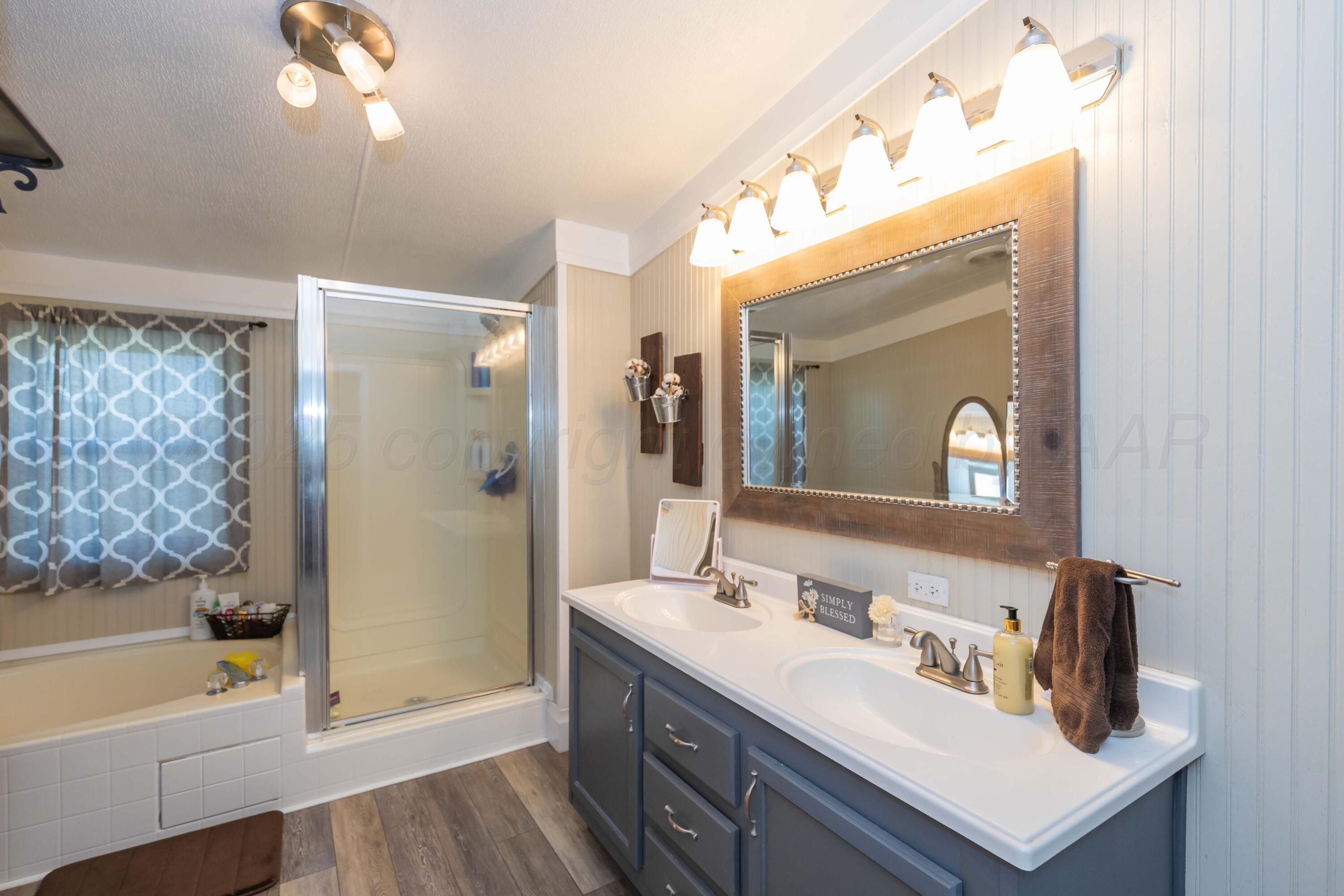 7501 Lobo Trail Amarillo, TX 79124 - Photo 36 of 49 a bathroom with a bathtub a sink and a large mirror