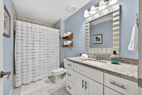 a bathroom with a granite countertop toilet sink and mirror