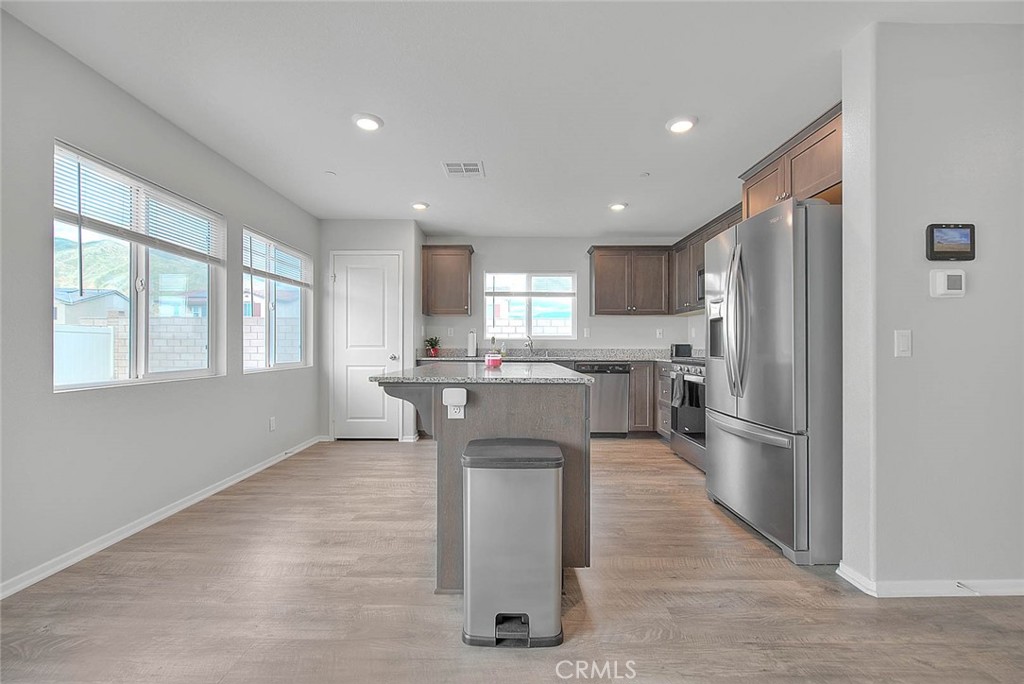 885 Canopy Lane San Jacinto, CA 92583 - Photo 46 of 75 a kitchen with stainless steel appliances kitchen island granite countertop a refrigerator oven a sink dishwasher and white cabinets with wooden floor