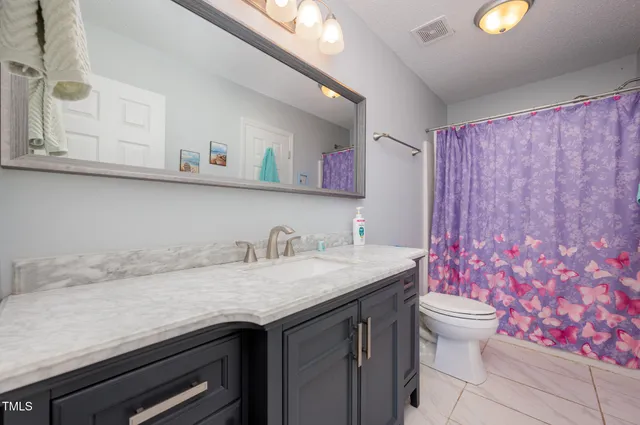 a bathroom with a granite countertop sink and a toilet