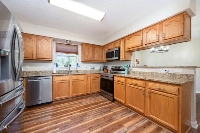 a kitchen with stainless steel appliances granite countertop a stove sink and cabinets