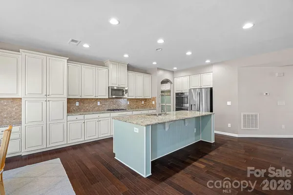 a kitchen with stainless steel appliances granite countertop a white cabinets and wooden floor
