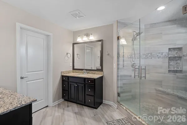a bathroom with a granite countertop sink a mirror and shower