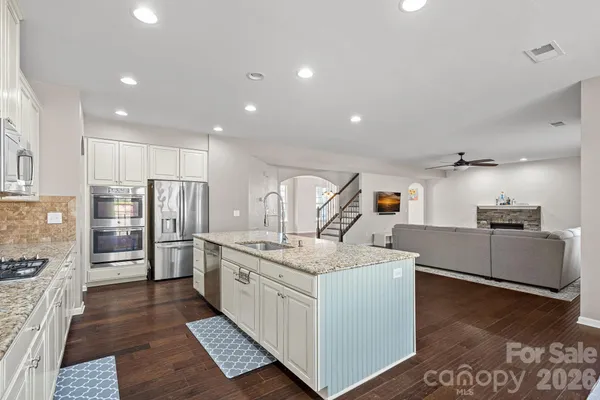 a kitchen that has a lot of white cabinets and stainless steel appliances