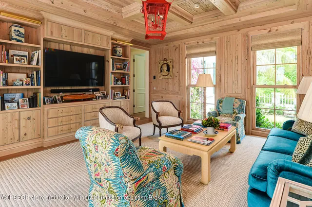 a living room with furniture a flat screen tv and floor to ceiling window