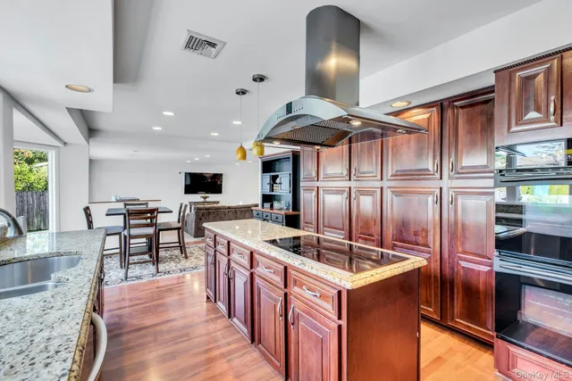 a kitchen with stainless steel appliances kitchen island granite countertop a table chairs in it and wooden floors