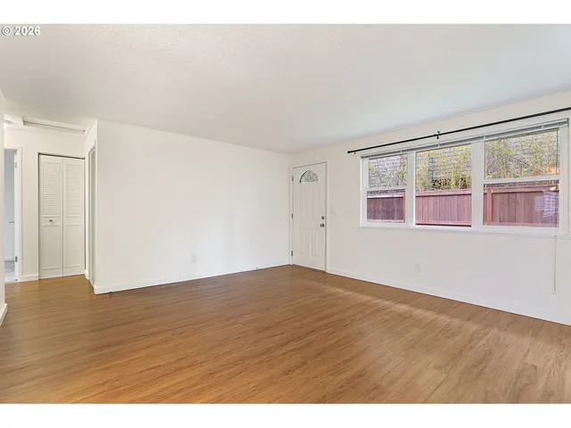 a view of an empty room with wooden floor and windows
