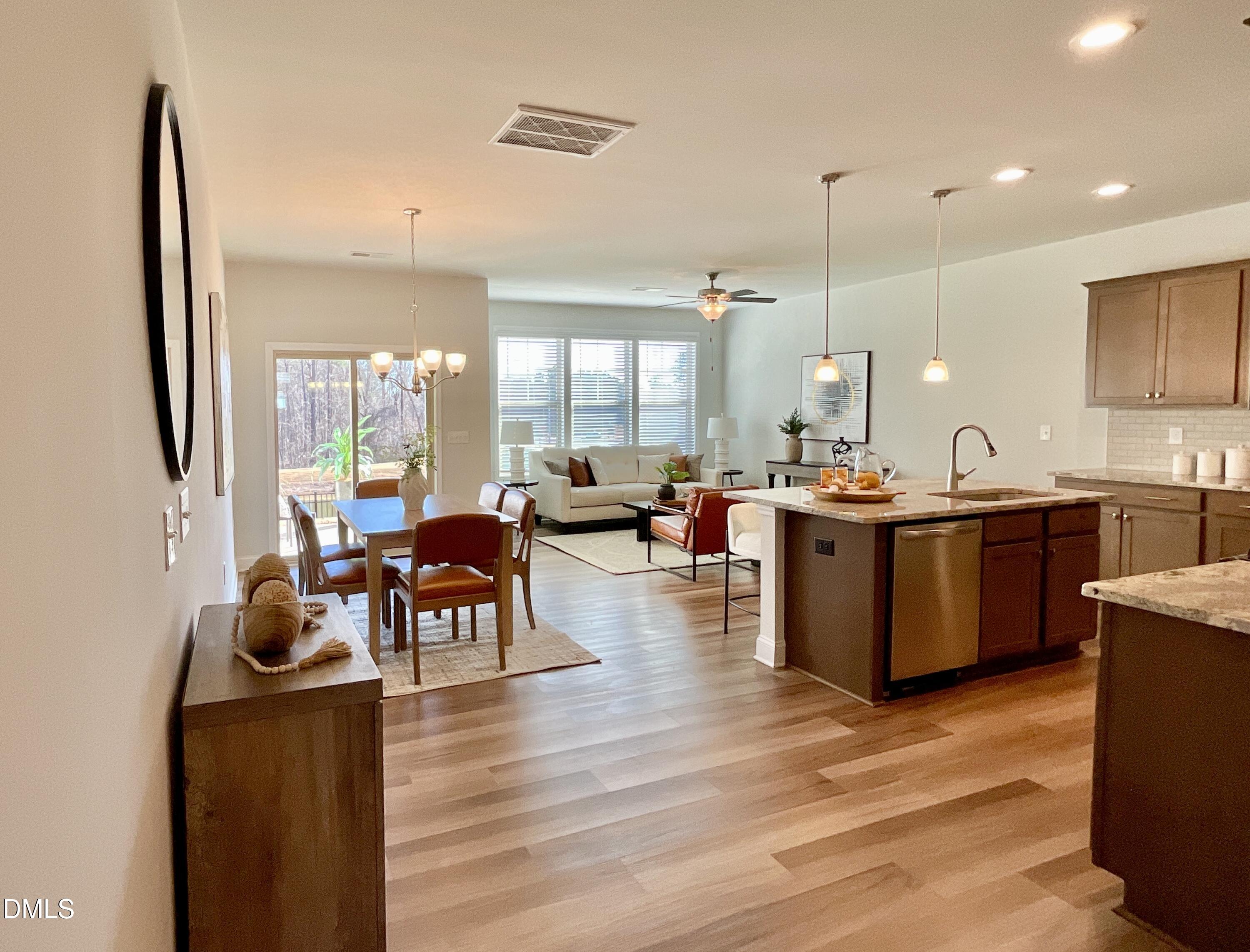1135 Longitude Drive Durham, NC 27713 - Photo 3 of 37 a open kitchen with stainless steel appliances kitchen island granite countertop a stove a sink a dining table and chairs with wooden floor