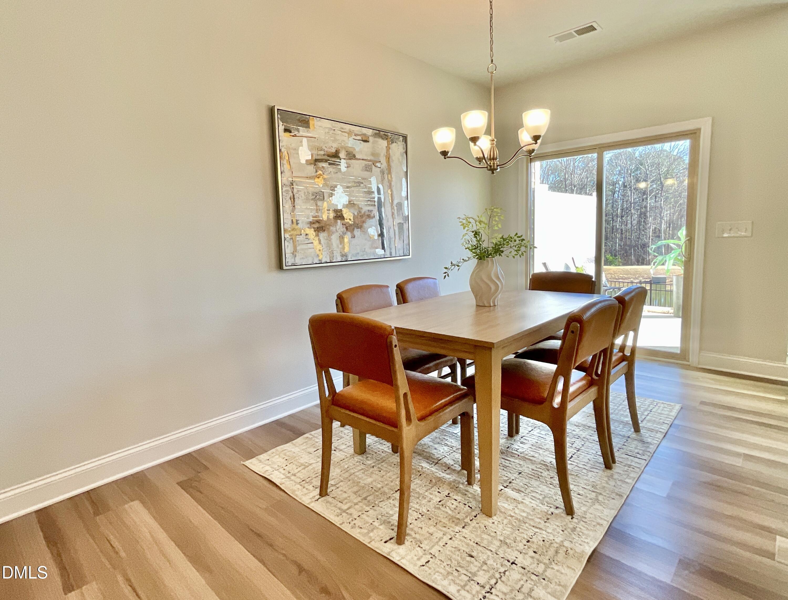 1135 Longitude Drive Durham, NC 27713 - Photo 5 of 37 a dining room with wooden floor a chandelier a wooden table and chairs