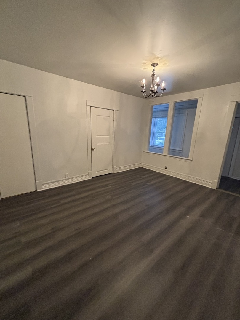 15634 Union Avenue Harvey, IL 60426 - Photo 6 of 34 an empty room with wooden floor chandelier and windows
