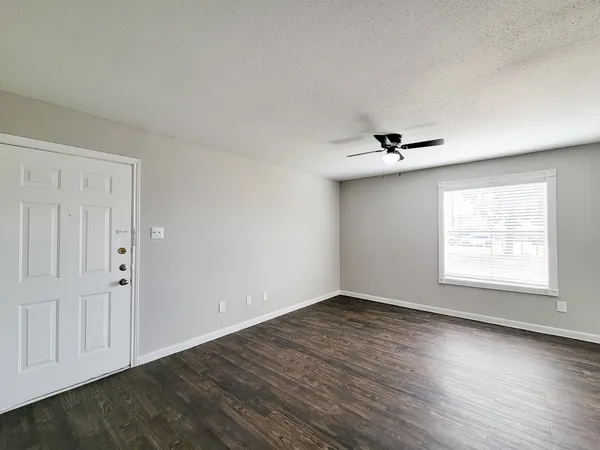 an empty room with wooden floor cabinet and windows