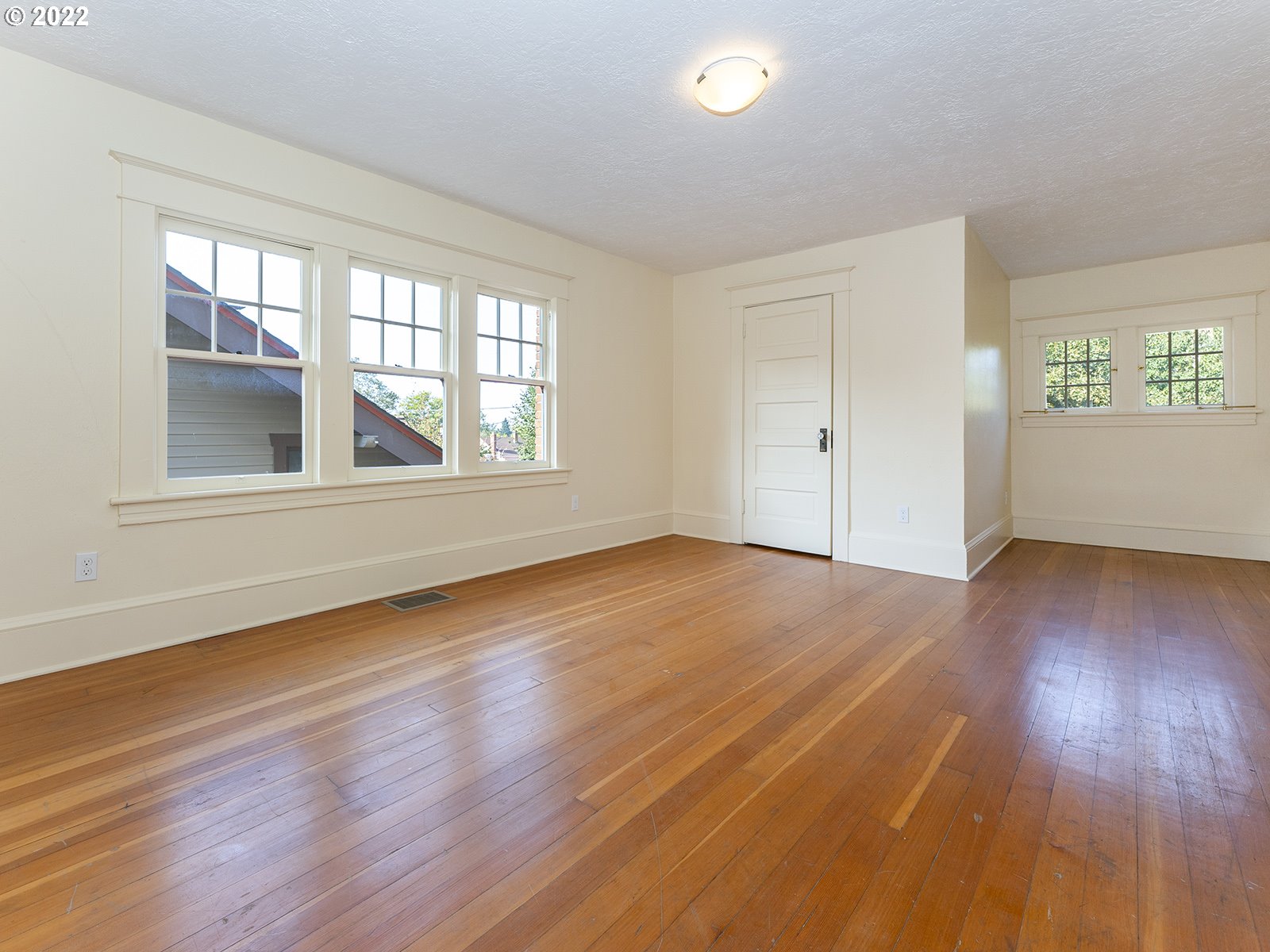 2424 Southeast Caruthers Street Portland, OR 97214 - Photo 18 of 32 an empty room with wooden floor and windows