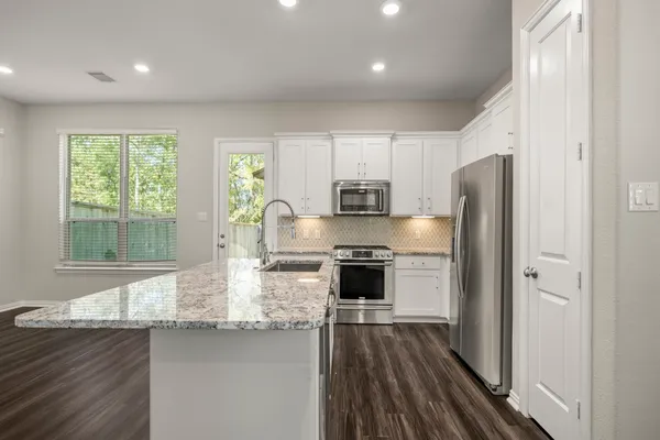 a kitchen with stainless steel appliances kitchen island granite countertop a stove a sink and a refrigerator