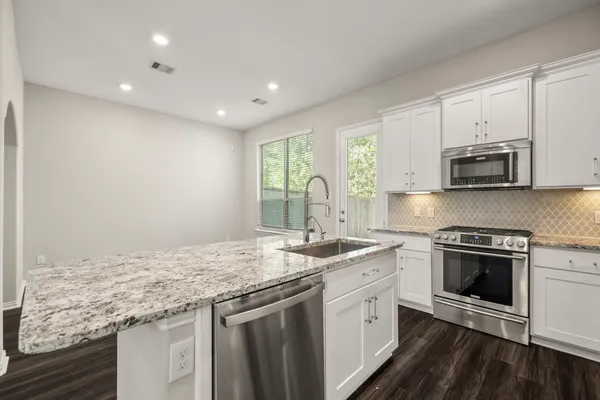 a kitchen with stainless steel appliances granite countertop a sink stove and microwave