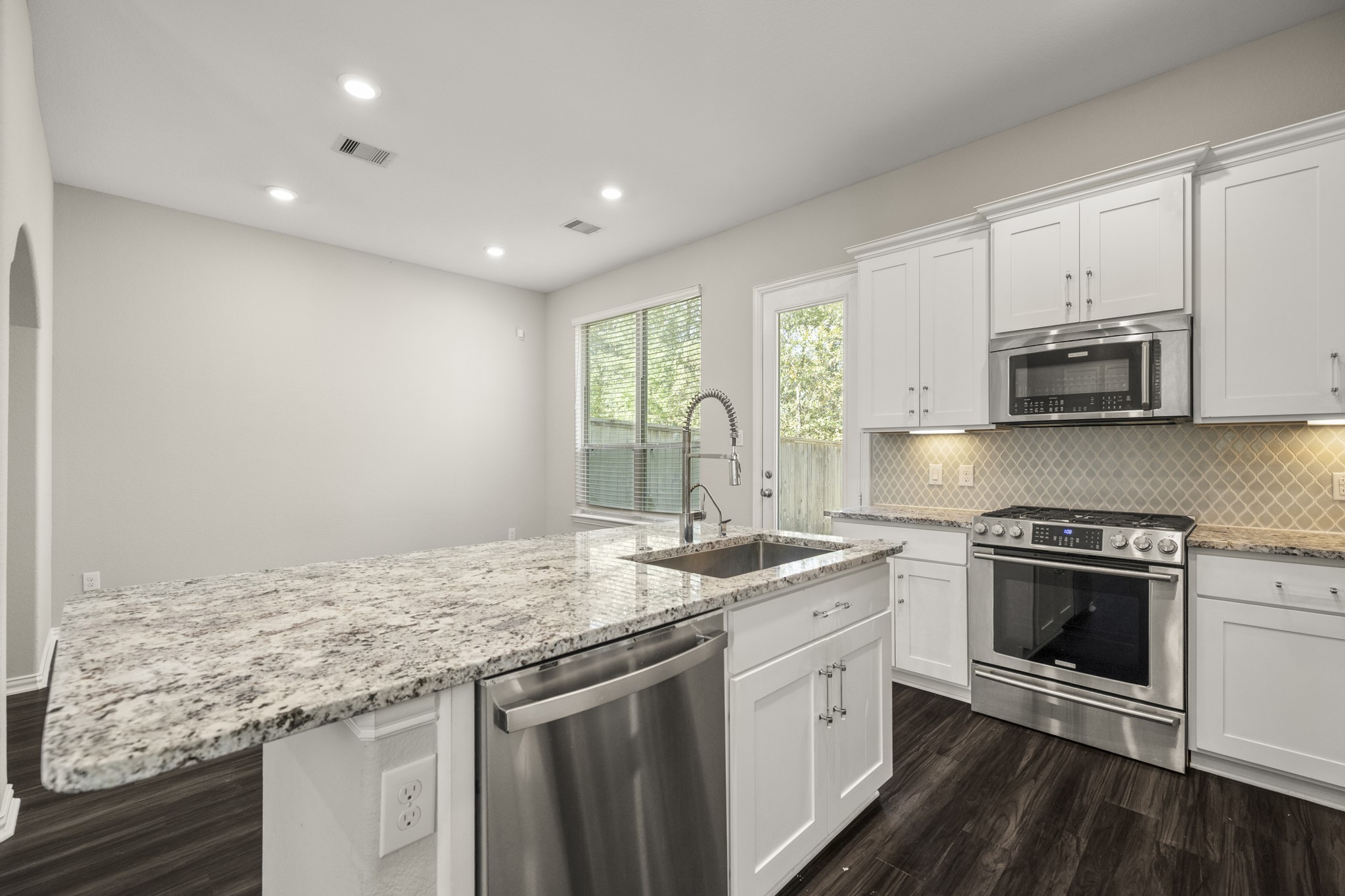 162 Moon Dance Court Conroe, TX 77304 - Photo 8 of 36 a kitchen with stainless steel appliances granite countertop a sink stove and microwave