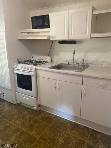 a kitchen with granite countertop a sink a stove and cabinets