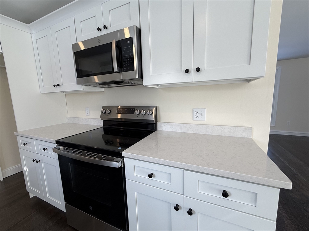 30 Alroy Road Weymouth, MA 02190 - Photo 18 of 40 a kitchen with white cabinets and black appliances
