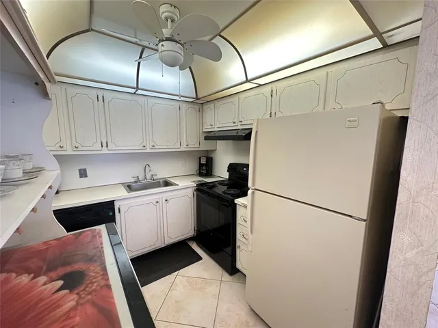 a kitchen with stainless steel appliances granite countertop a refrigerator a sink and white cabinets