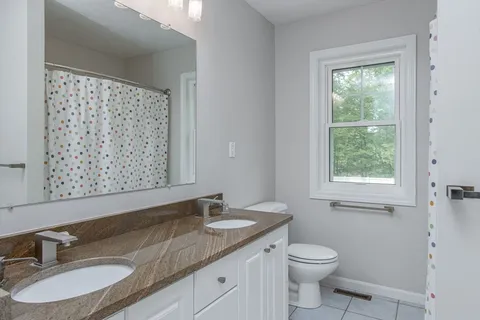 a bathroom with a granite countertop sink toilet and mirror