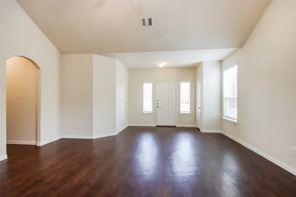 an empty room with wooden floor and windows
