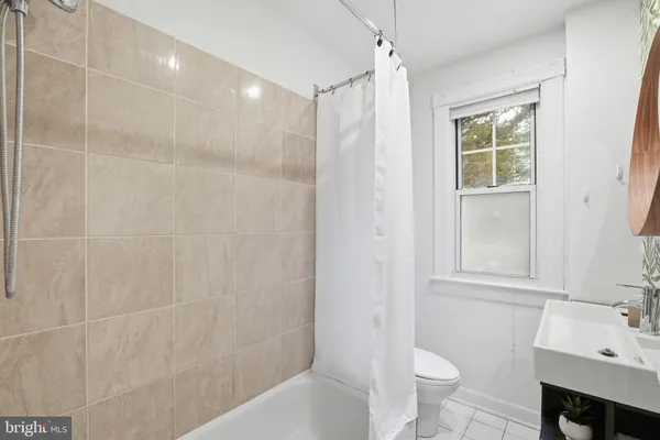 a bathroom with a bathtub shower sink vanity and a toilet