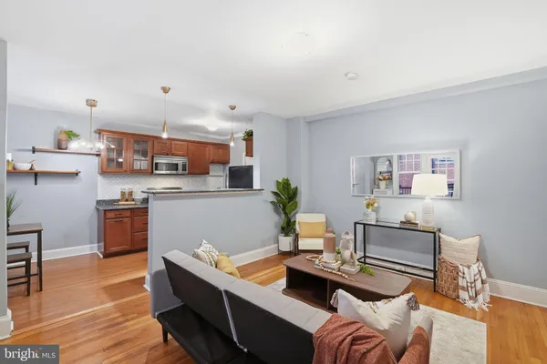 a living room with stainless steel appliances kitchen island granite countertop furniture and a wooden floor