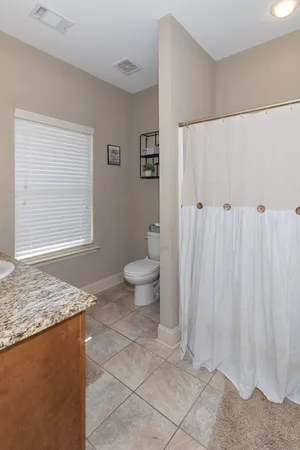 a bathroom with a granite countertop sink and a toilet