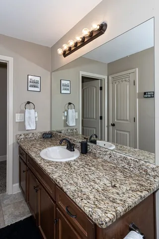 a bathroom with a granite countertop sink and a wooden floor
