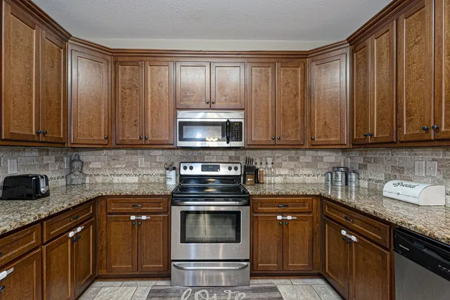 a kitchen with granite countertop a stove top oven microwave and cabinets