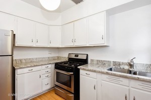 7231 North Ridge Boulevard, Unit 1E Chicago, IL 60645 - Photo 4 of 9 a kitchen with granite countertop white cabinets and a stove