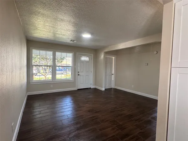 an empty room with wooden floor and windows