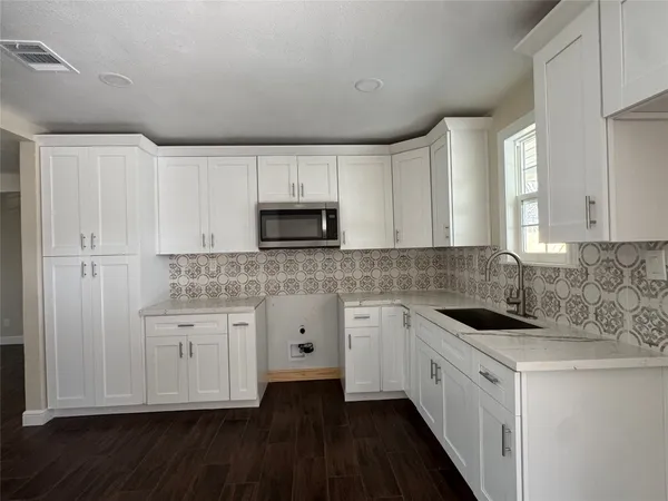 a kitchen with white cabinets appliances and sink