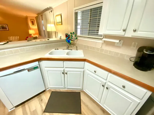 a view of a kitchen with a sink and a dishwasher a stove top oven with wooden floor