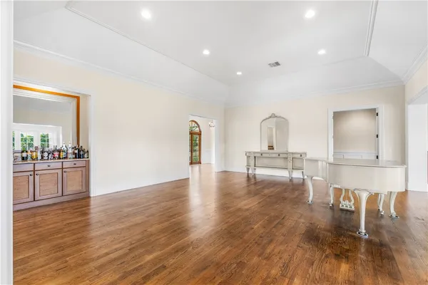 a view of empty room with wooden floor and kitchen view